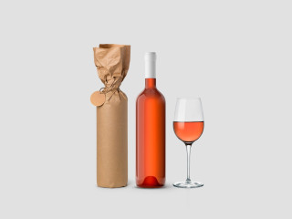 Weinflasche in Papier eingewickelt mit Etikett und Glas auf weißem Hintergrund