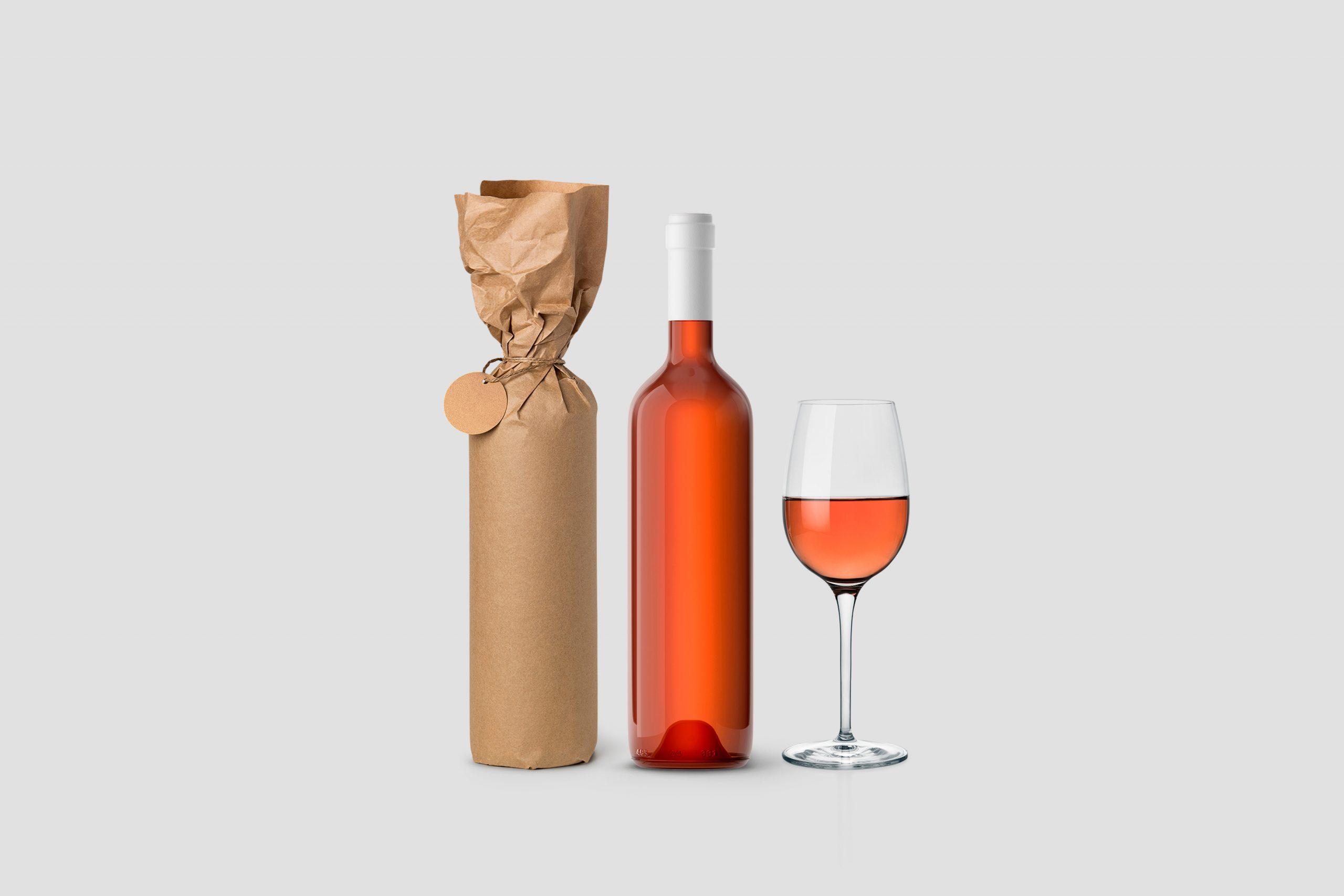 Weinflasche in Papier eingewickelt mit Etikett und Glas auf weißem Hintergrund